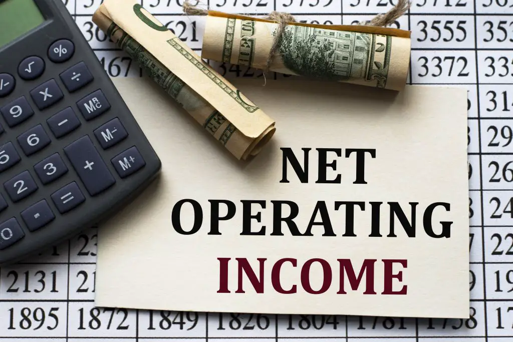 Calculating Cap Rate for NET OPERATING INCOME - words on white paper against the background of a table of numbers with a calculator and banknotes. Business and finance concept